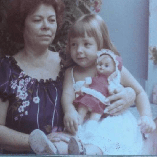 Andressa as a little girl in Brazil, sitting with her grandmother